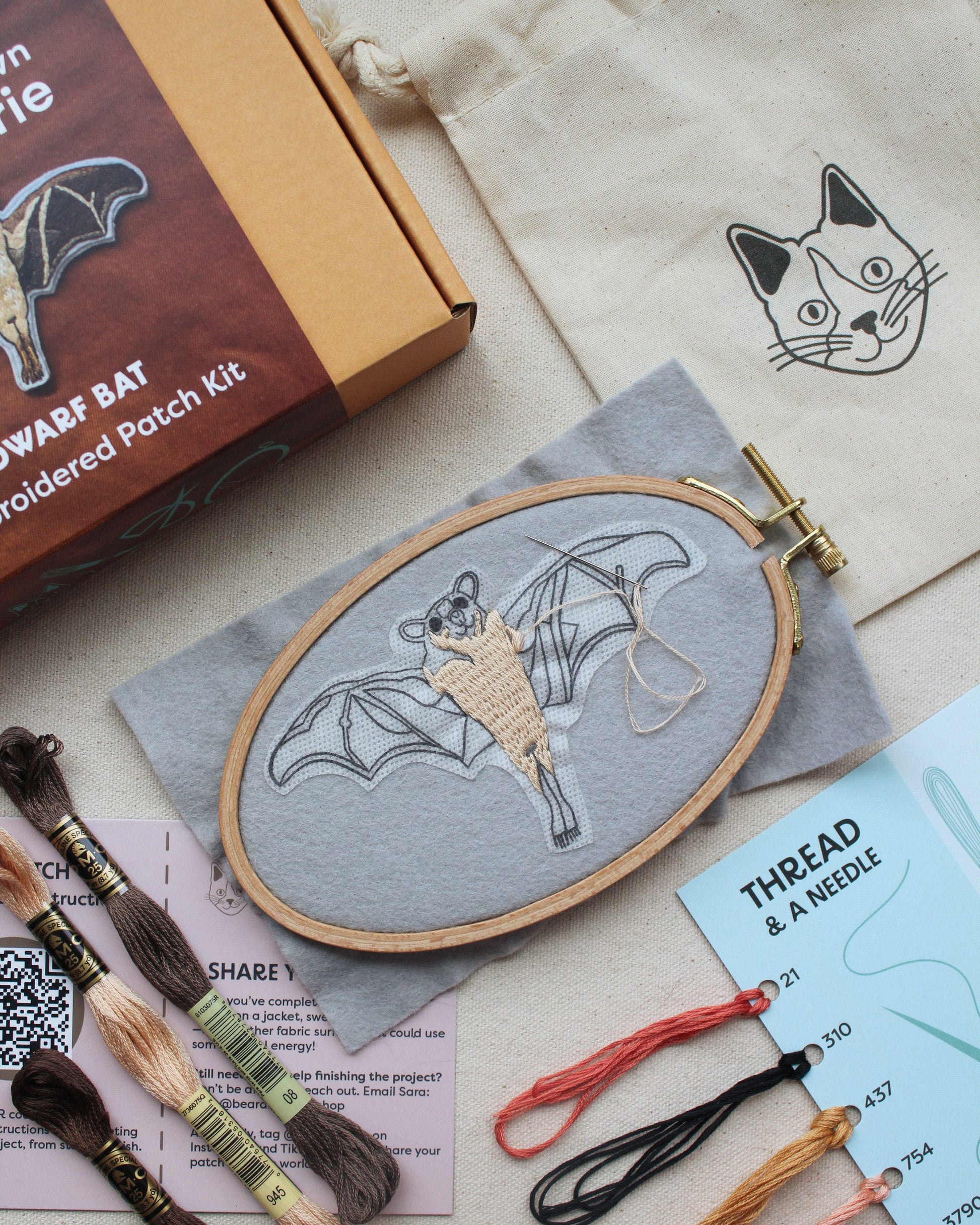 Embroidery kit with bat design, threads, and needle on a neutral background
